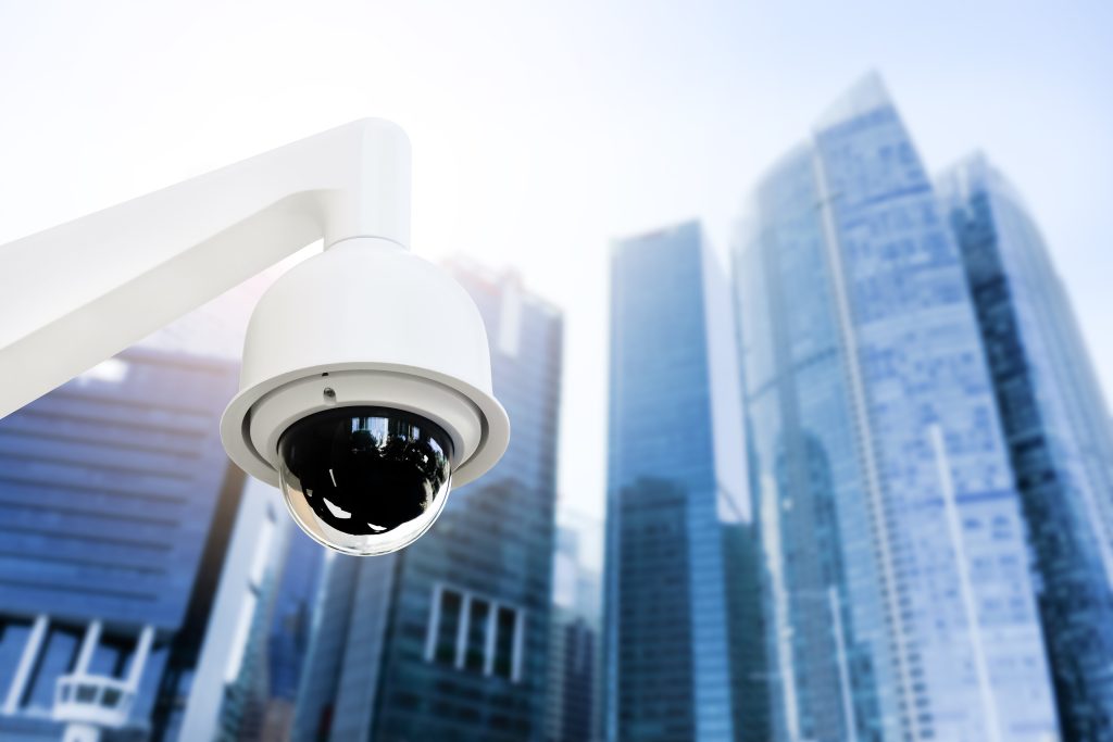 Modern public CCTV camera on electric pole with blur building background and copy space.
